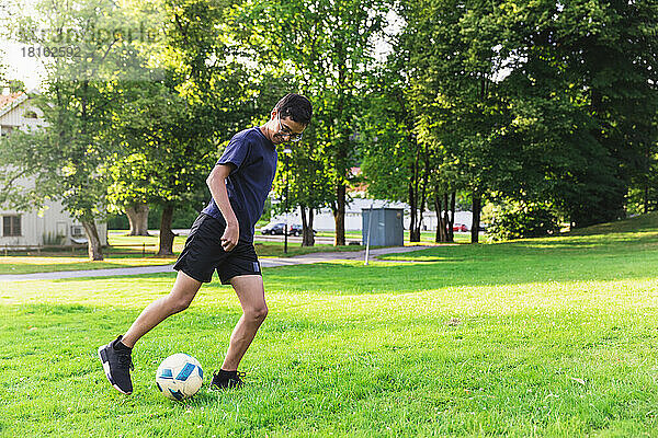 Junge spielt Fußball auf Gras im Rasen