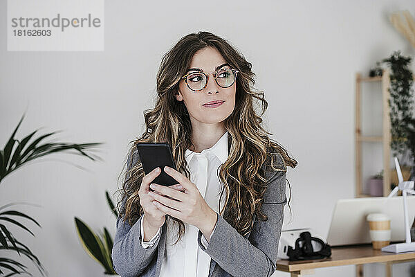 Nachdenkliche Geschäftsfrau benutzt Mobiltelefon im Büro
