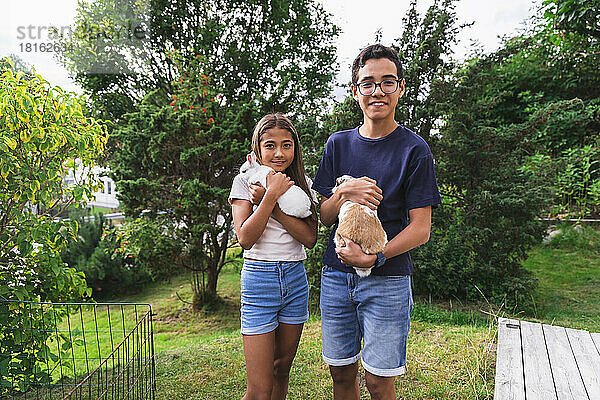 Bruder und Schwester halten Kaninchen im Hinterhof