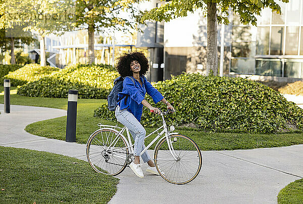 Lächelnde Afro-Frau mit Fahrrad auf Fußweg im Park