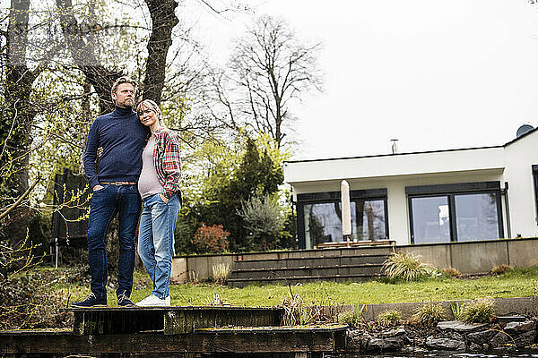 Werdendes Paar steht auf Steg vor Haus