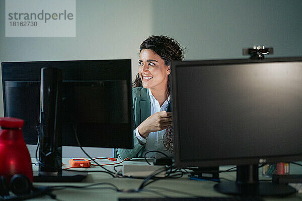 Lächelnde Geschäftsfrau sitzt am Computertisch