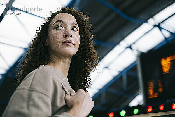 Young woman with curly hair at train station