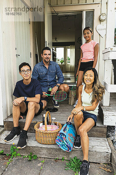 Gemischtrassige Familie mit Picknickzubehör auf der Veranda