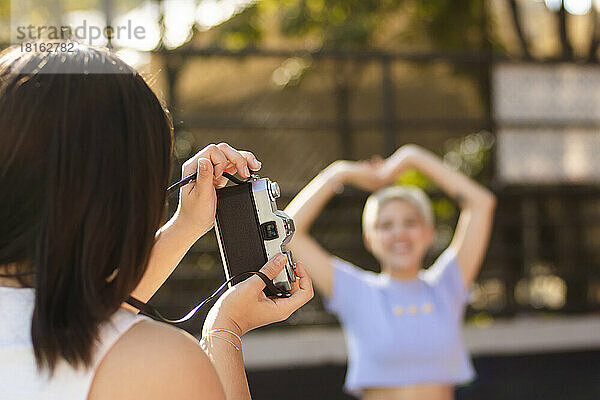 Junge Frau fotografiert an einem sonnigen Tag einen Freund mit der Kamera