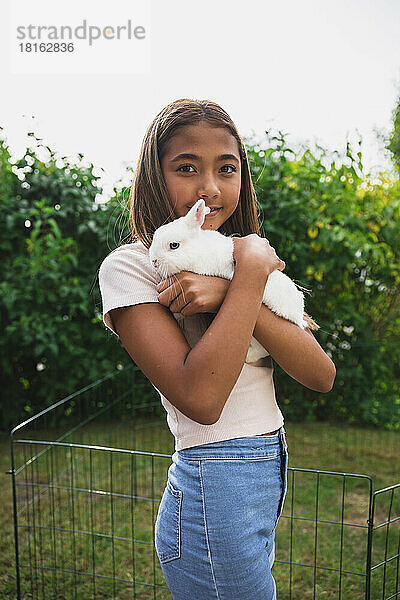 Mädchen hält Kaninchen im Hinterhof