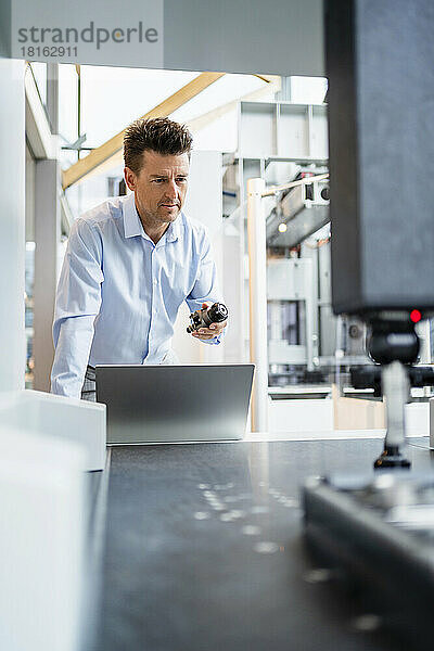 Geschäftsmann hält Ausrüstung vor Laptop