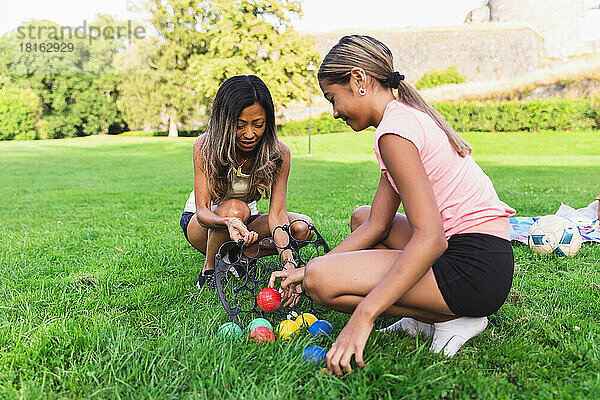Mutter und Tochter spielen Boule und hocken im Gras