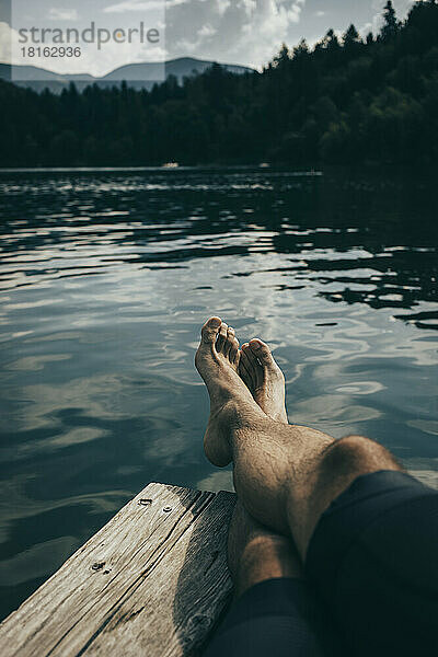 Mann mit gekreuzten Beinen entspannt sich auf dem Steg am Montigglersee