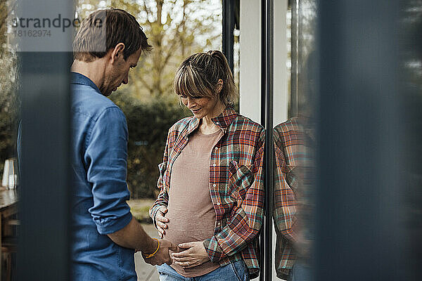 Mann blickt auf schwangeren Bauch einer Frau