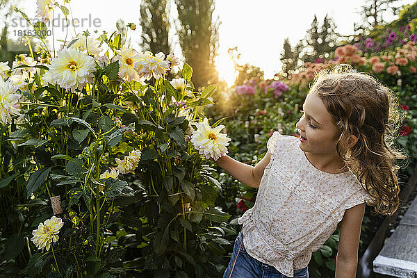Kleines Mädchen riecht Blumen im Garten