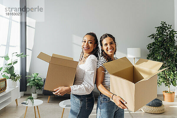 Lächelnde Mitbewohner mit Kartons im Wohnzimmer