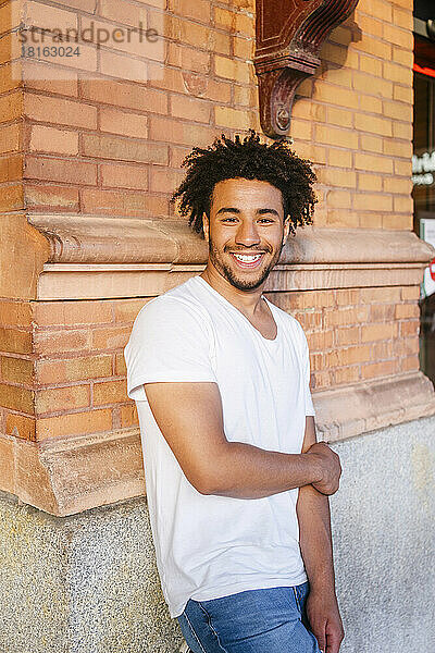 Smiling young man leaning on wall