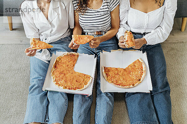 Mitbewohner sitzen zusammen zu Hause und essen Pizza