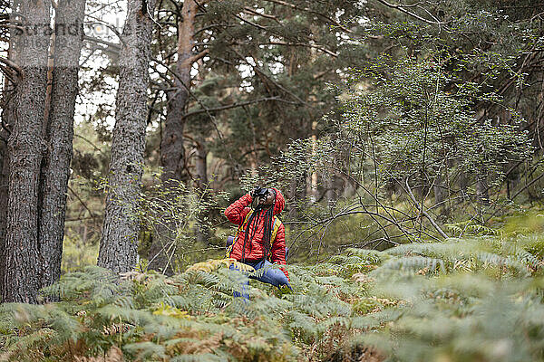 Junge Frau fotografiert mit der Kamera im Wald