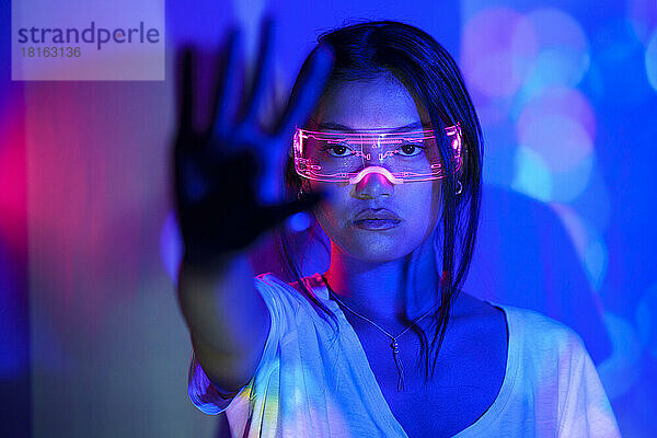 Junge Frau mit futuristischer Brille zeigt Handfläche