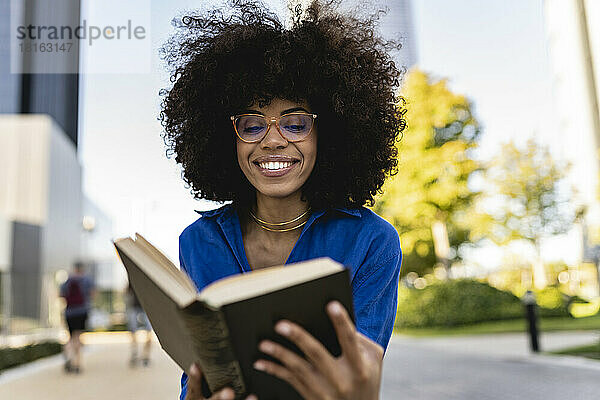 Lächelnde Afro-Frau mit Brille und Lesebuch