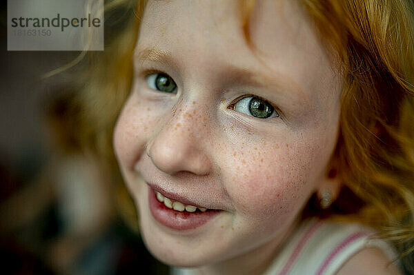 Lächelndes rothaariges Mädchen mit Sommersprossen im Gesicht