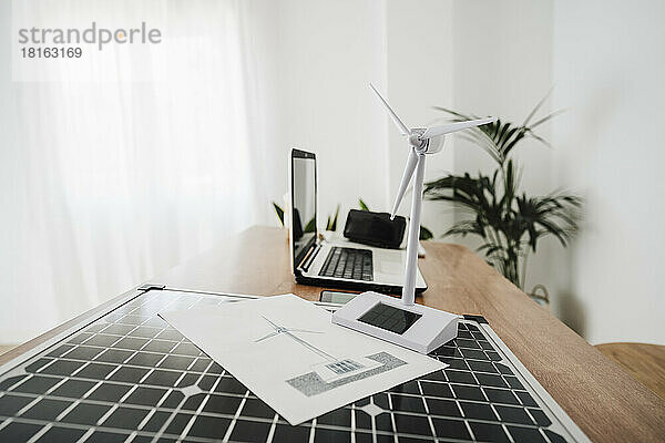 Tragbares Solarpanel und Windturbinenmodell auf dem Schreibtisch des Ingenieurs