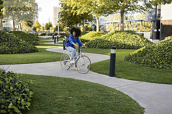 Lächelnde Frau mit Fahrrad auf Fußweg im Park