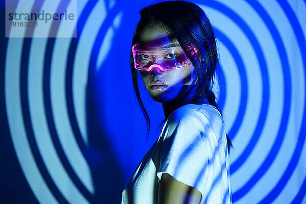 Young woman with futuristic glasses under spiral shadow