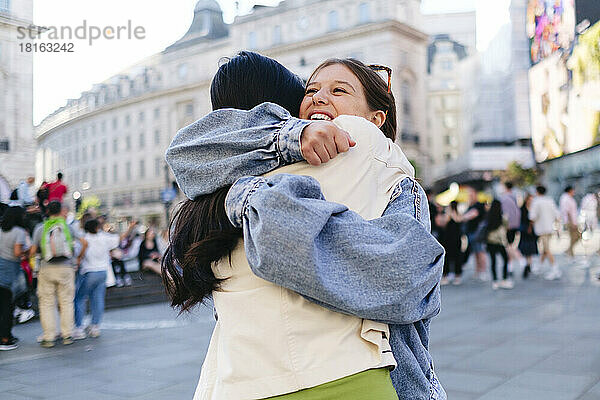 Happy woman embracing lesbian friend in city
