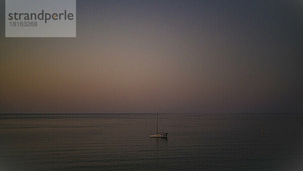 Segelboot auf ruhiger See in der Abenddämmerung