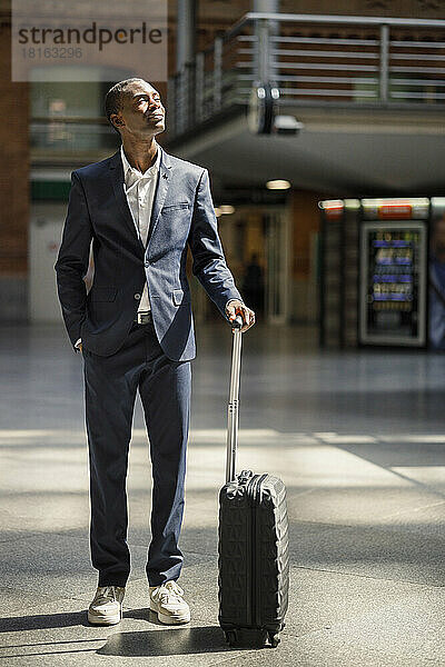 Businessman standing with luggage at railroad station