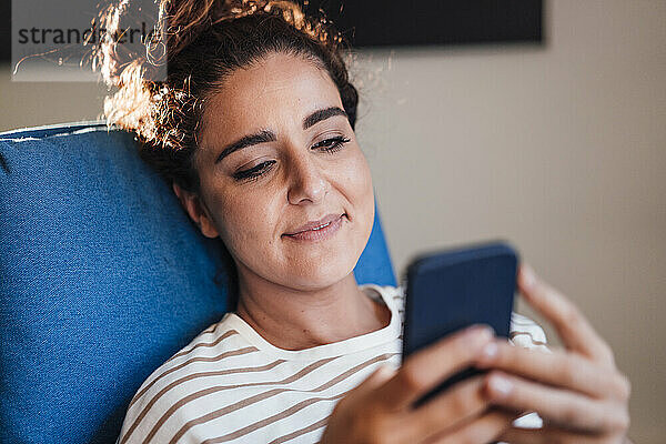 Frau schreibt zu Hause SMS über ihr Smartphone