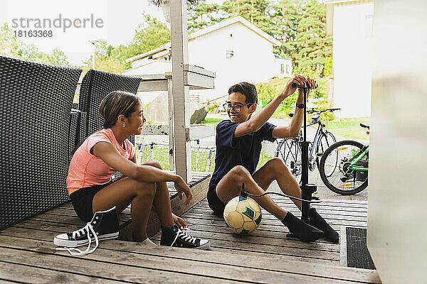 Bruder und Schwester bereiten sich auf das Fußballspielen auf der Veranda vor