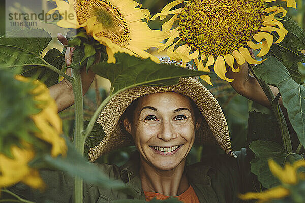 Glückliche Frau inmitten von Sonnenblumen im Garten