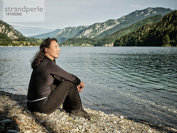 Nachdenkliche Frau entspannt sich am Seeufer