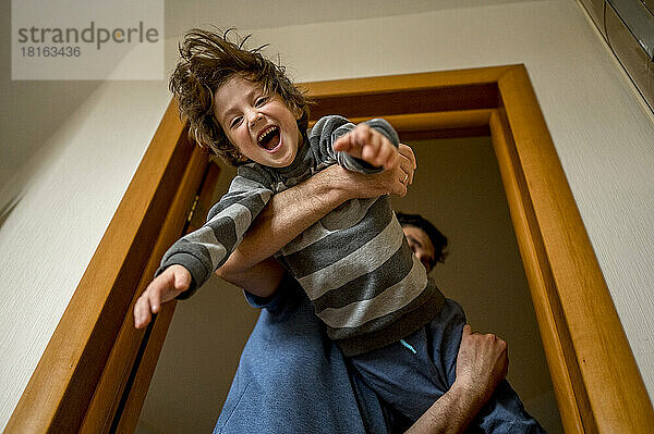 Playful father lifting son at home