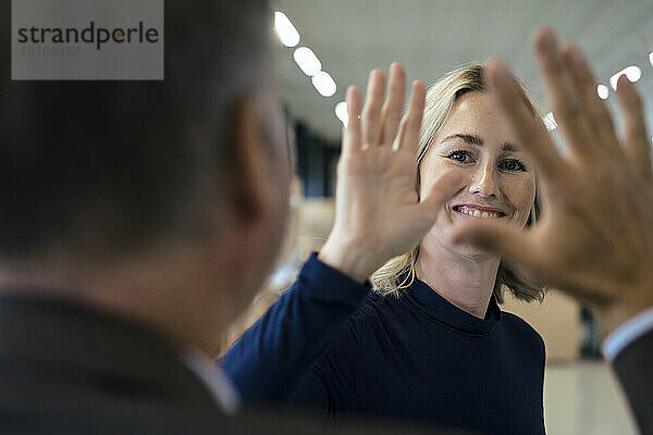 Happy businesswoman giving high-five to colleague