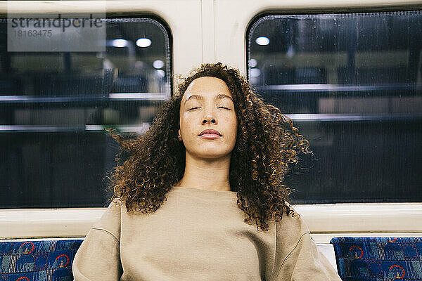 Frau mit geschlossenen Augen entspannt sich in der U-Bahn