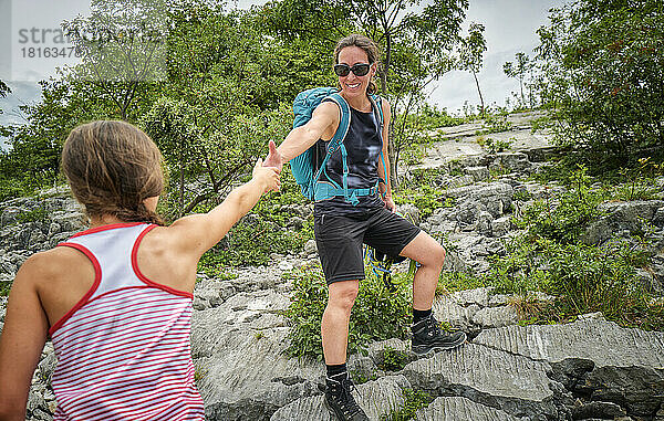 Glückliche Frau hält die Hand ihrer Tochter beim Bergsteigen