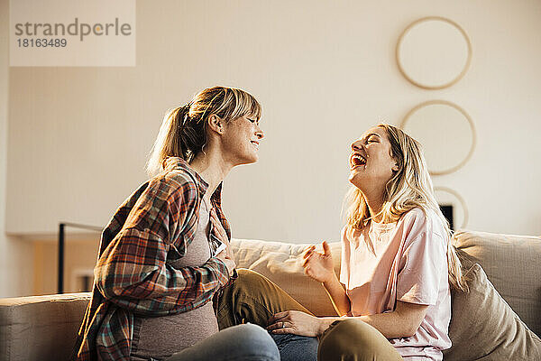 Happy woman enjoying with pregnant sister at home