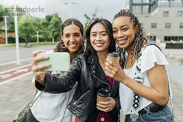 Smiling woman taking selfie with friends on smart phone