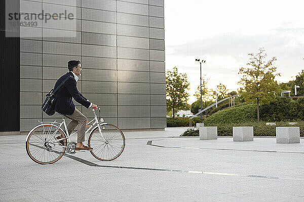 Geschäftsmann fährt Fahrrad vor Bürogebäude