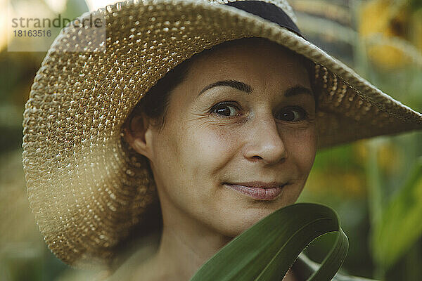 Lächelnde Frau mit Hut im Garten