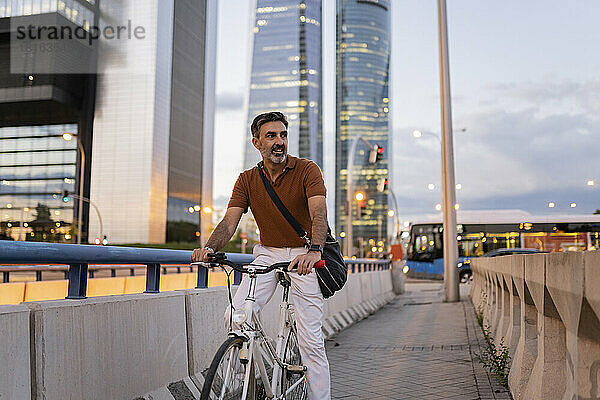 Geschäftsmann mit Fahrrad auf Fußweg in der Stadt