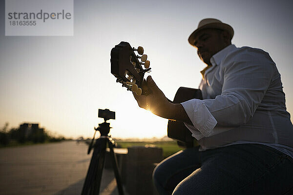Gitarrist spielt Gitarre bei Sonnenuntergang