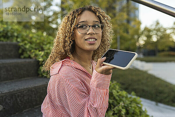 Junge Frau spricht über Lautsprecher-Smartphone