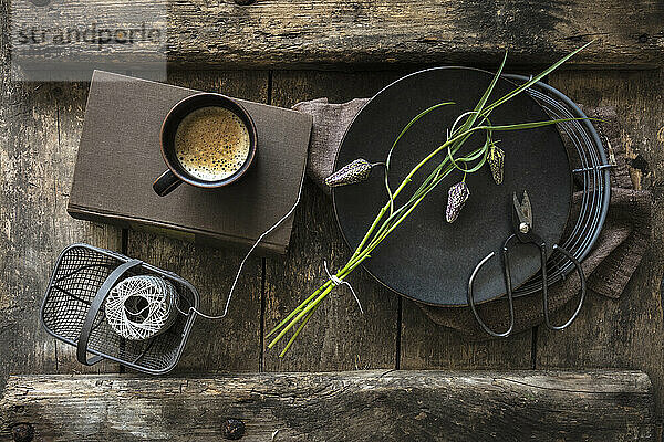 Frisch geschnittene Schlangenkopffritillarien (Fritillaria meleagris) und eine Tasse Kaffee auf einem rustikalen Holztisch
