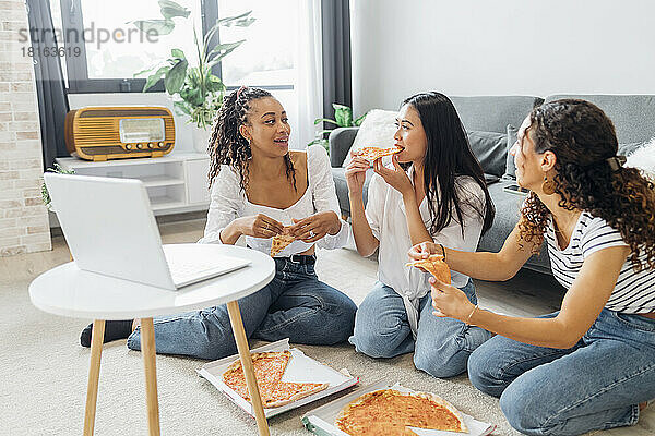 Freunde essen Pizza und genießen gemeinsam im Wohnzimmer