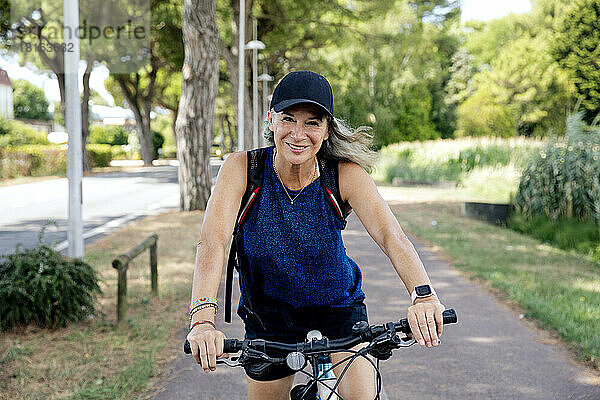 Lächelnde ältere Frau mit Fahrrad auf Fußweg