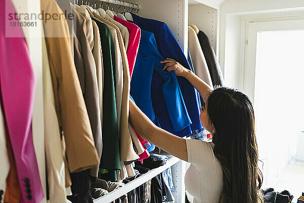 Frau wählt Kleidung im Schrank aus
