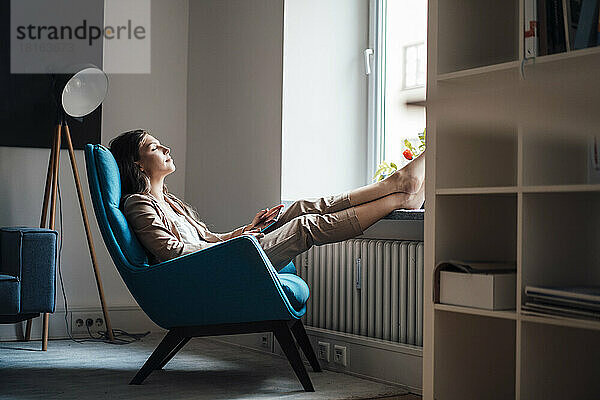 Geschäftsfrau entspannt sich zu Hause auf einem Stuhl