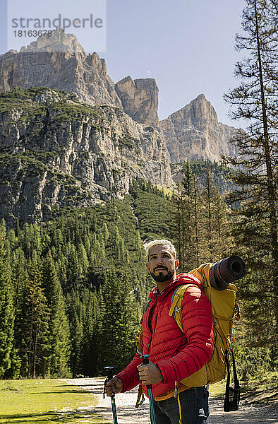 Wanderer mit Rucksack und Wanderstöcken steht vor den Dolomiten  Italien