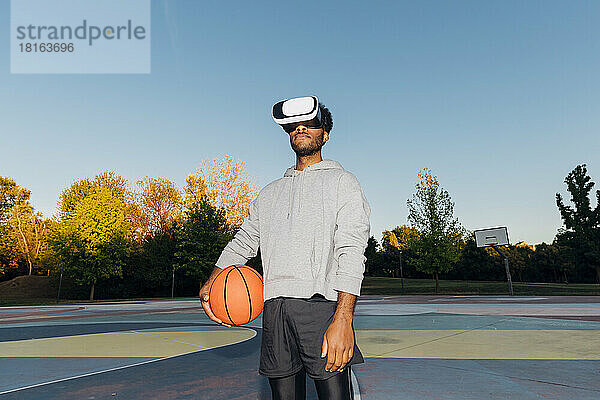 Sportler mit Basketball und VR-Brille auf dem Sportplatz